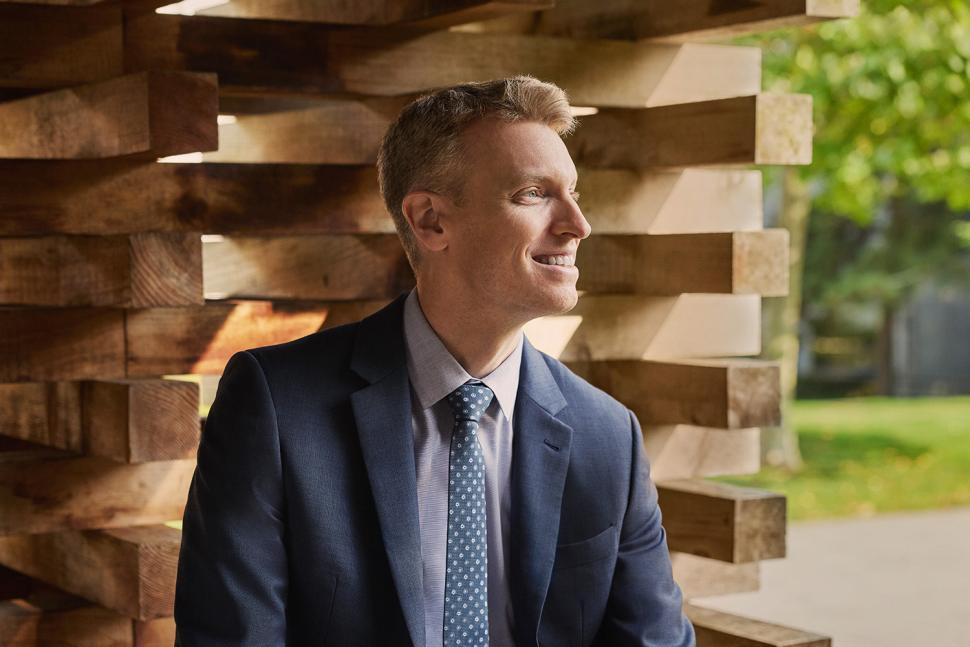 Dr Zachary Hudson in profile against outdoor wooden structure