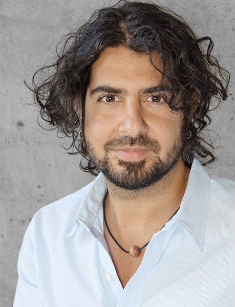 Portrait of Azim Shariff in white shirt against grey wall